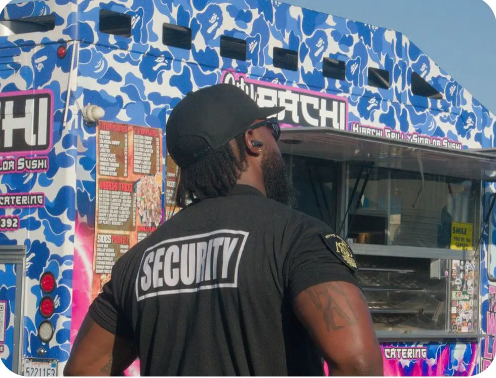 Security guard near colorful food truck.